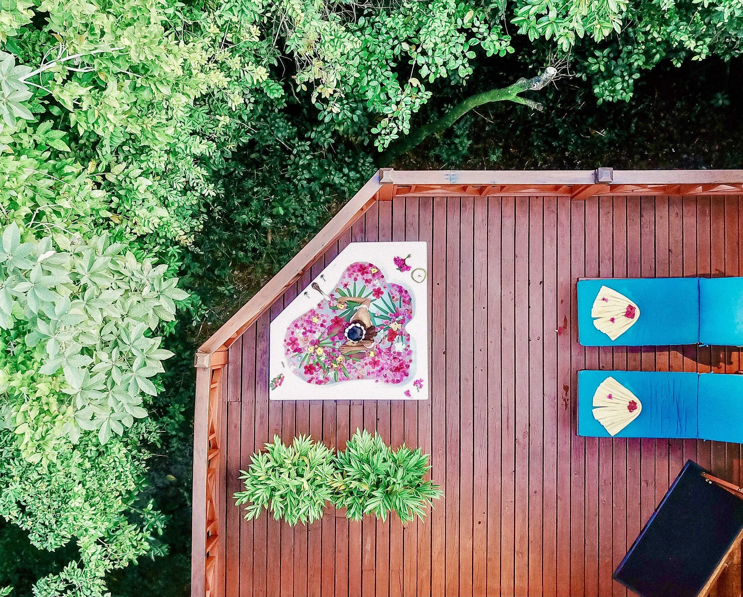 Flower petal bath on treehouse deck surrounded by jungle canopy