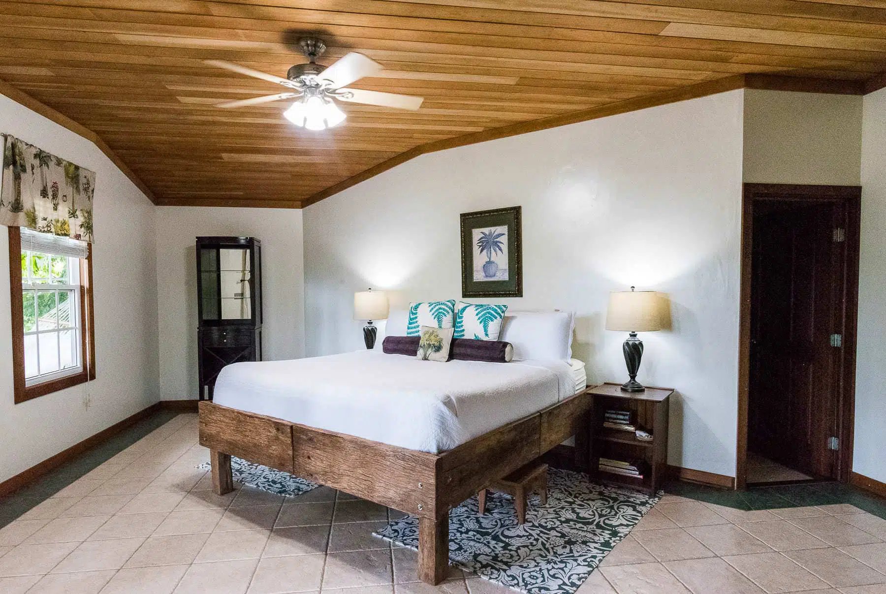 Spacious bedroom with king bed, wooden ceiling, and tropical décor at Tranquilo Bay